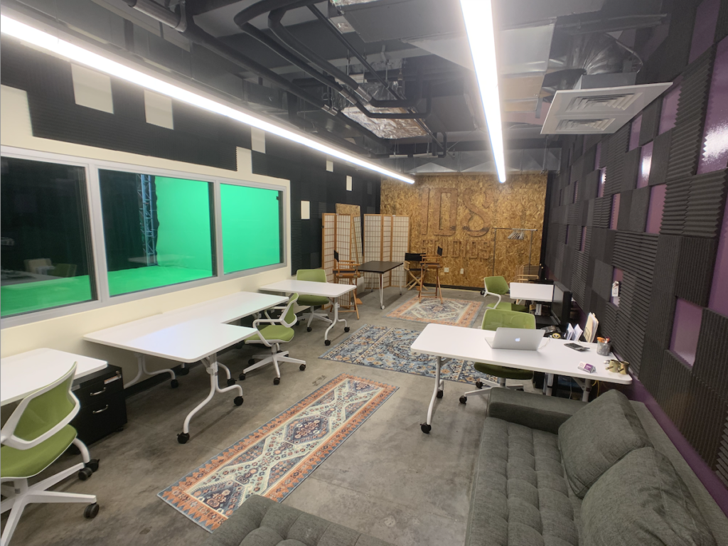 The collaboration room, with desks and acoustic panelling, looking through onto the green-screen stage